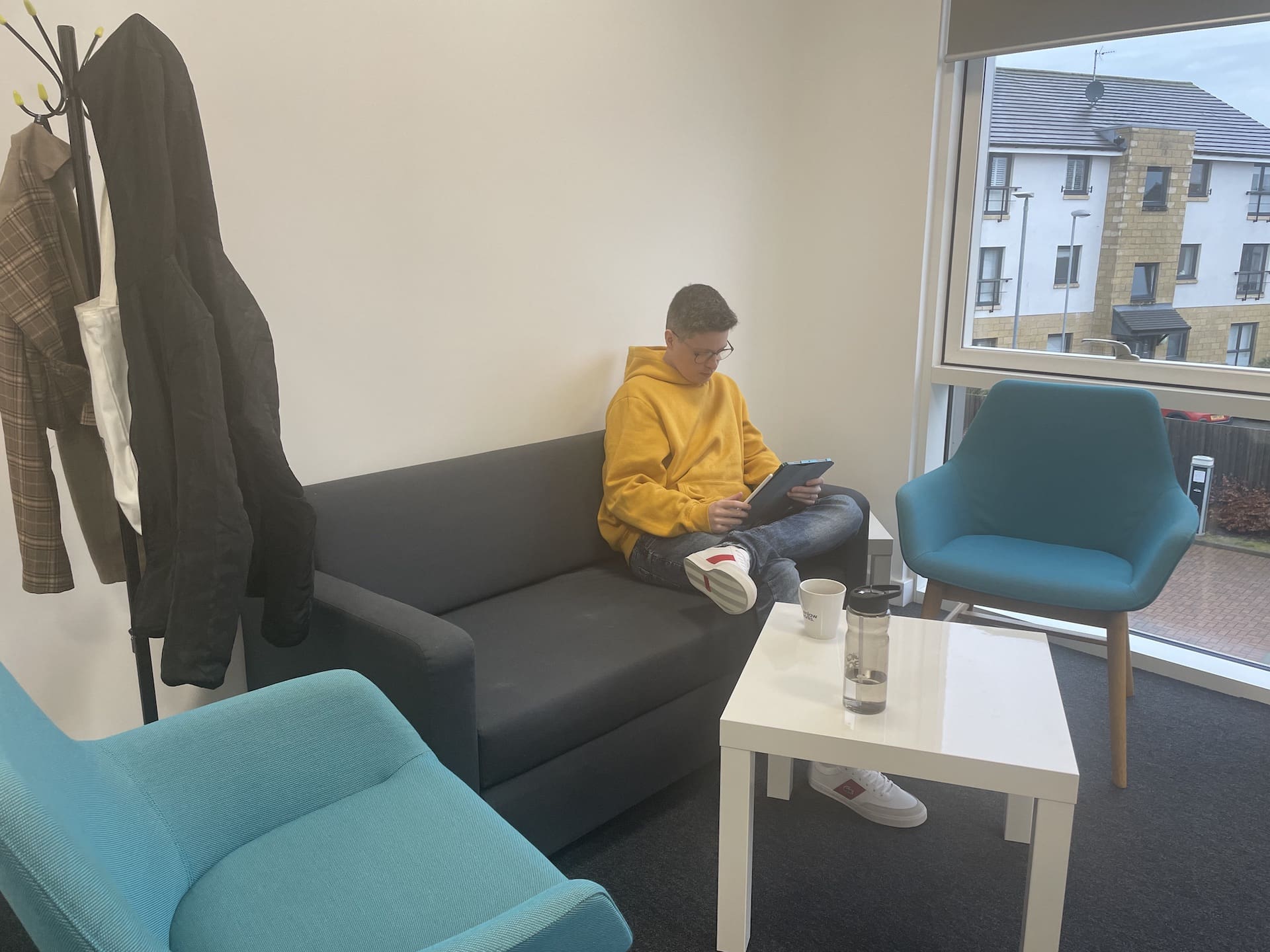 Scoot Managing Director Scott Sutherland sitting on a grey couch in a new office space.