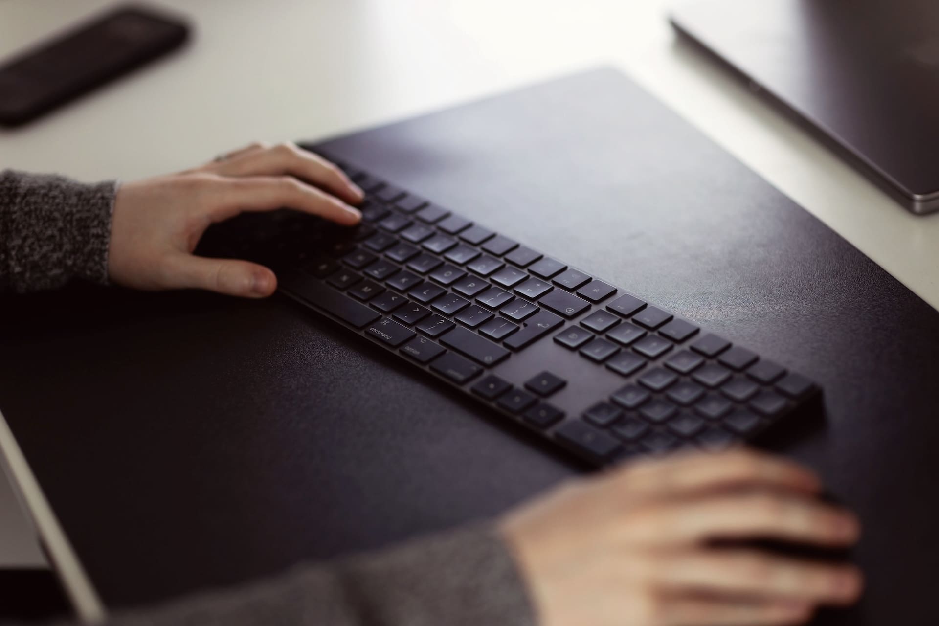 Hands poised over a black keyboard and mouse on a desk
