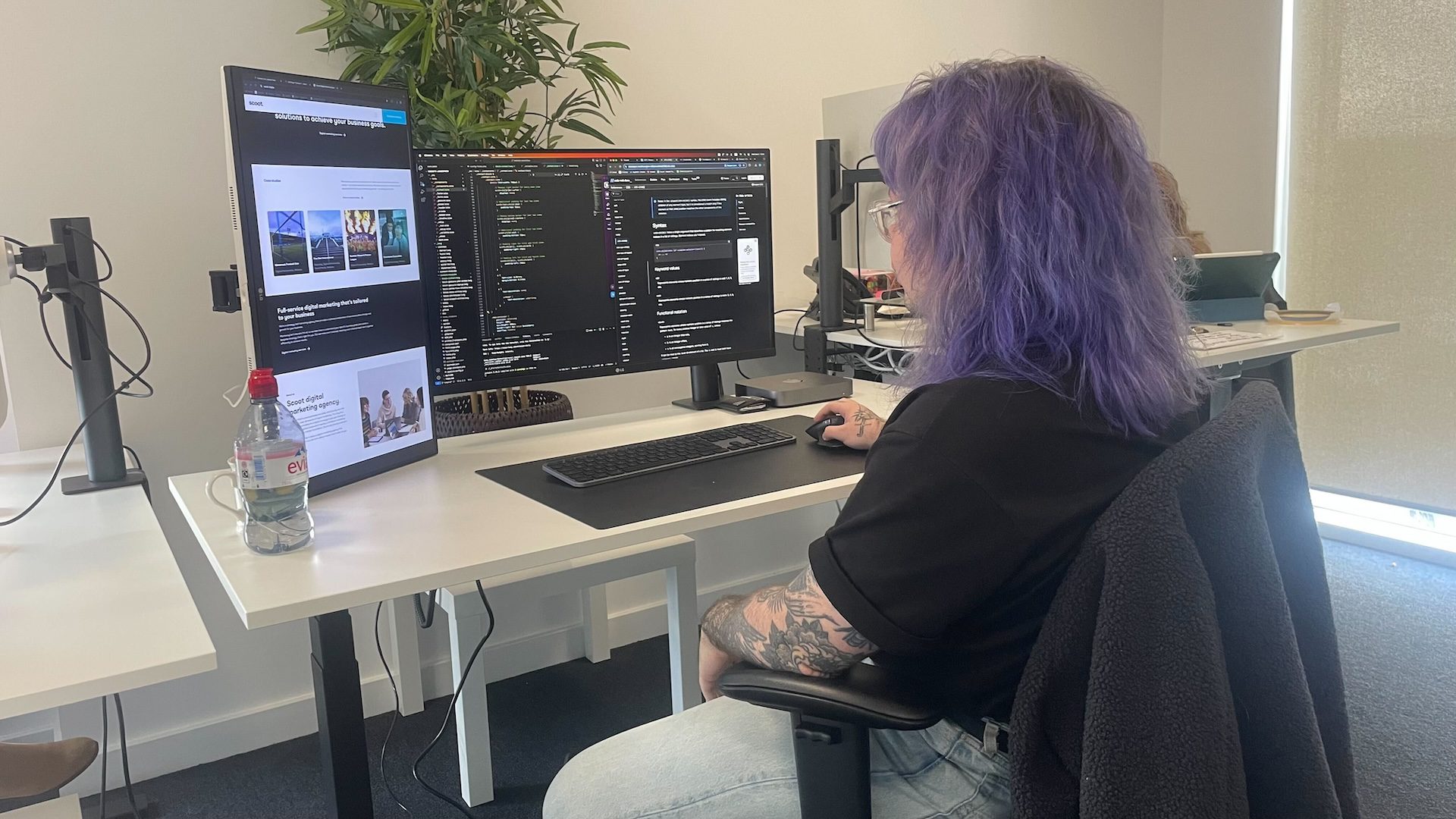 a man sitting at a desk with two computer screens